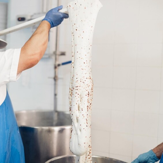 A person wearing blue gloves handling a long, white, speckled object. 1