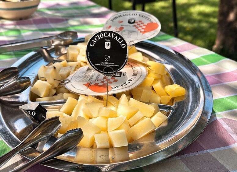 A metal plate with cubed cheese and a cheese container labeled 'Caciocavallo' on a checkered tablecloth. 1