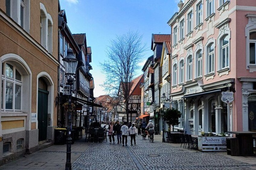 A cobblestone street lined with historic buildings, a clear sky, and pedestrians. 3