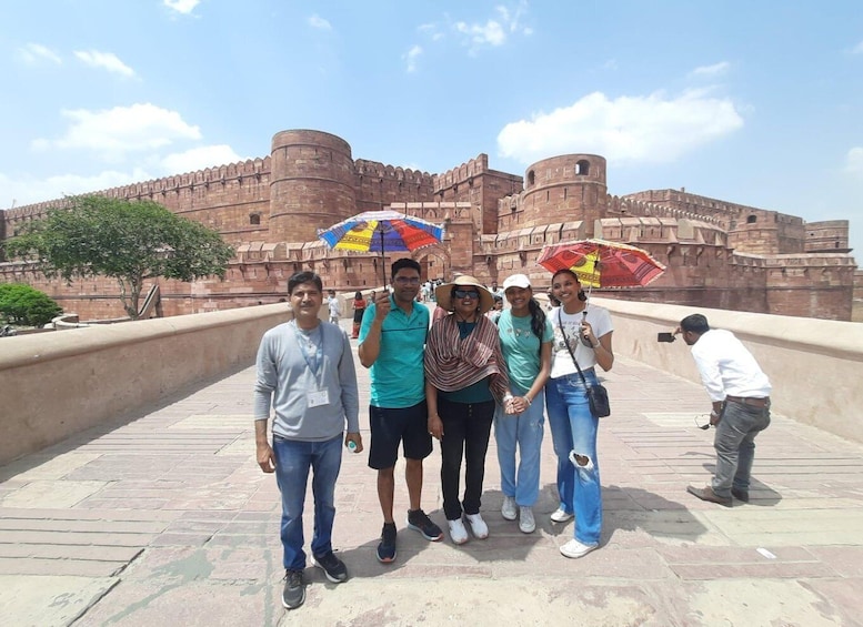 A group of people standing in front of a large, historic fort with a clear sky. 2