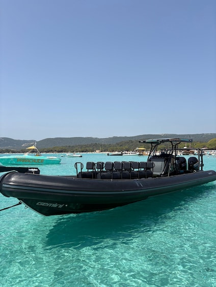 A Zodiac boat named 'GEMINI' on turquoise water with a clear sky and distant hills. 1