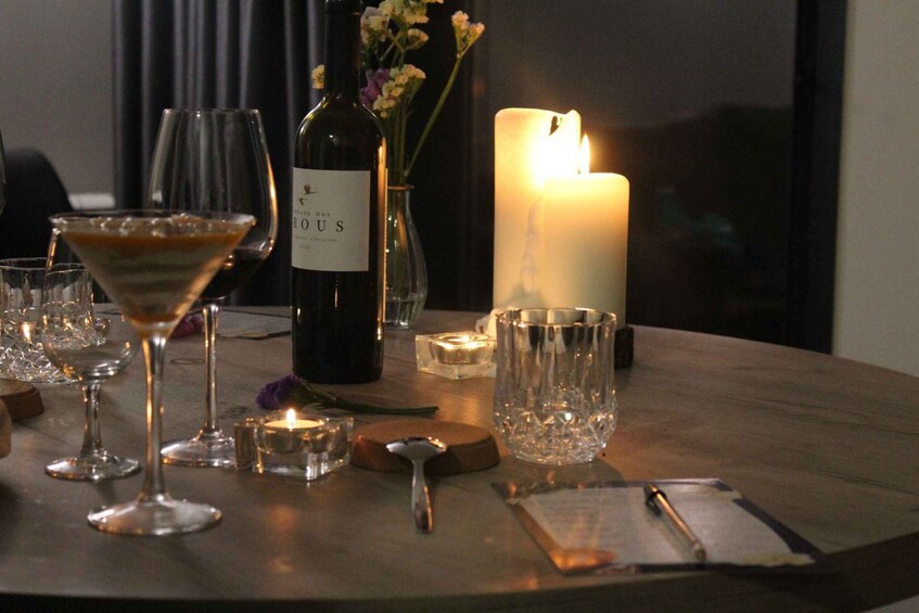 A table with wine glasses, a bottle, and a lit candle. 2