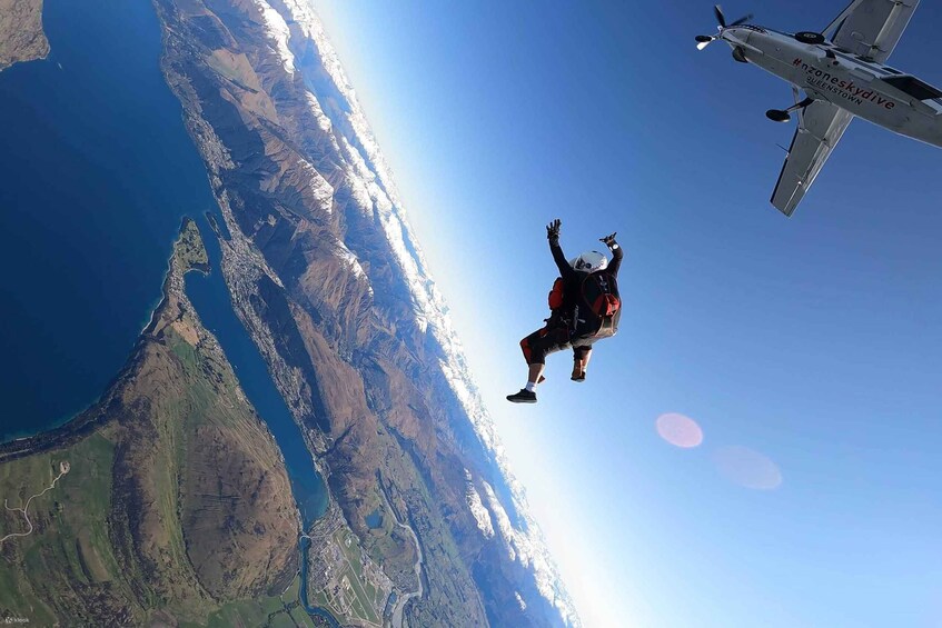 A person skydiving with a parachute, an airplane in the background, and a mountainous landscape below. 5