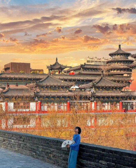 A traditional Chinese architectural complex with tiered roofs and a person holding a fan. 2