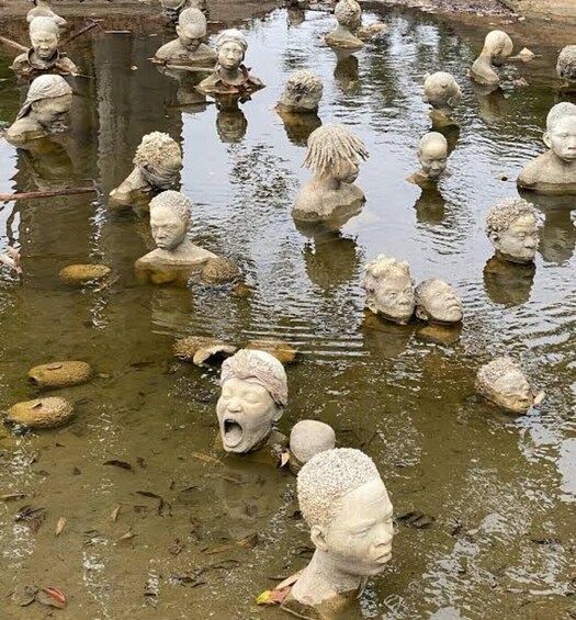 A pond with numerous stone sculptures of human heads. 3