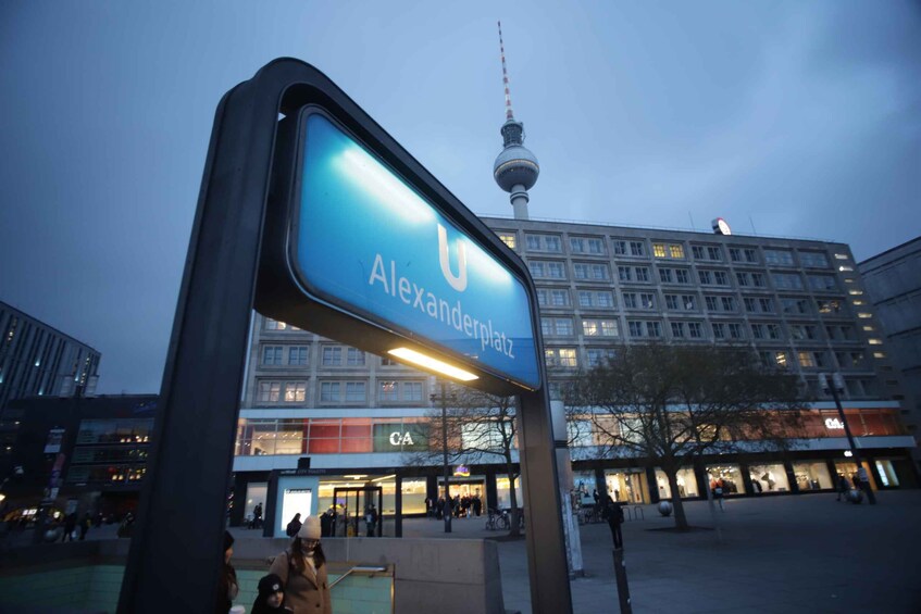 A large blue sign with 'Alexanderplatz' and a tower in the background. 1