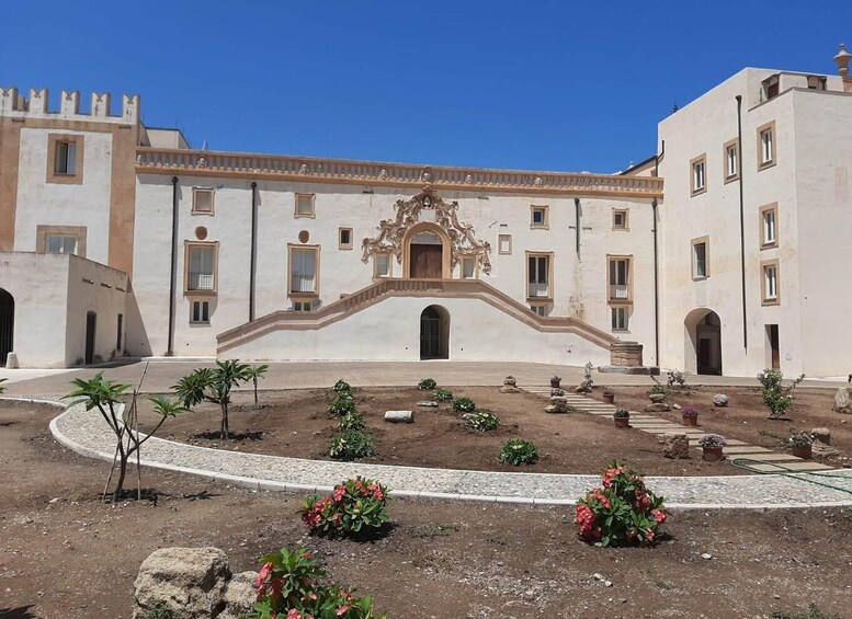 A historic building with a central courtyard, surrounded by smaller structures, and a clear blue sky above. 5