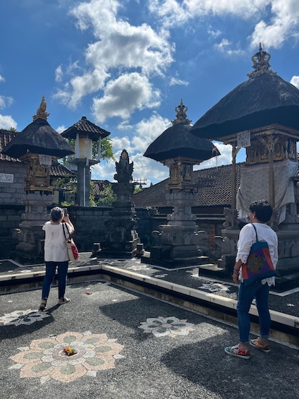 A temple complex with stone statues and thatched-roof structures under a clear sky. 5