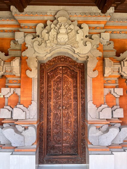 A detailed wooden door with intricate carvings, set within a stone structure with orange accents. 4