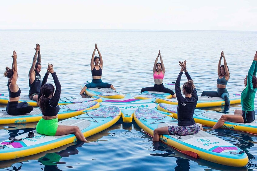 A group of people practicing yoga on surfboards in a body of water. 2