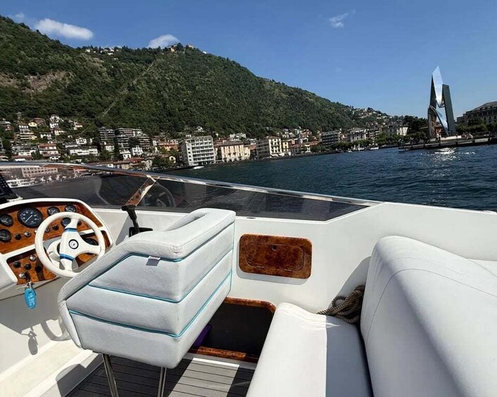 A boat's interior with a steering wheel, cushioned seats, and a view of a coastal town with buildings and a hill in the background. 3