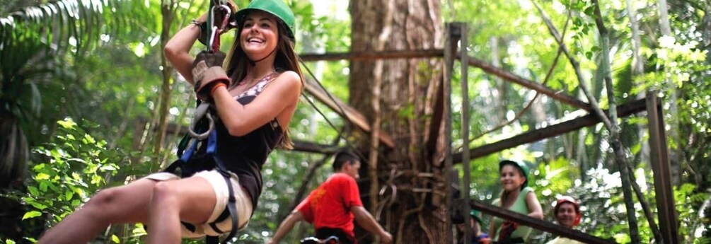 A person zip-lining through a forested area with rope bridges and trees. 4