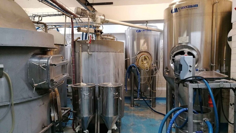 Industrial brewing equipment, stainless steel tanks, and piping in a brewery setting. 5