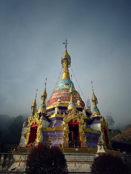A multi-tiered, ornate temple with golden spires and a blue and red roof. 2
