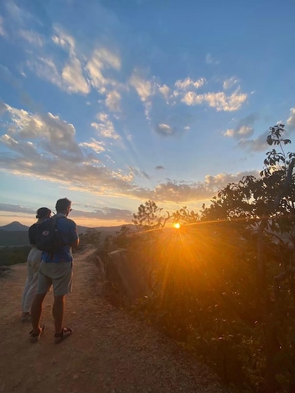A sunset over a mountainous landscape with a dirt path and vegetation. 1