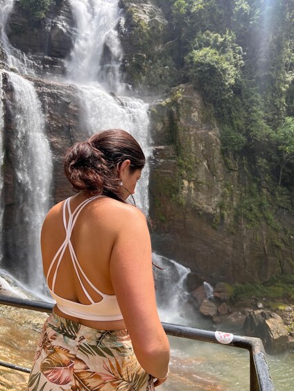 A person standing by a waterfall with a view of the surrounding rocky terrain. 1
