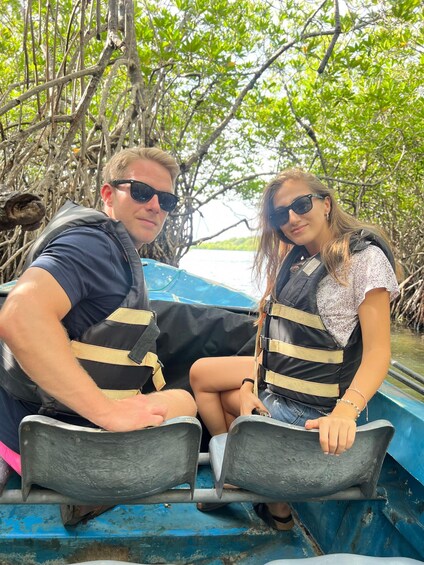 Two people wearing life jackets on a boat surrounded by mangrove trees. 5
