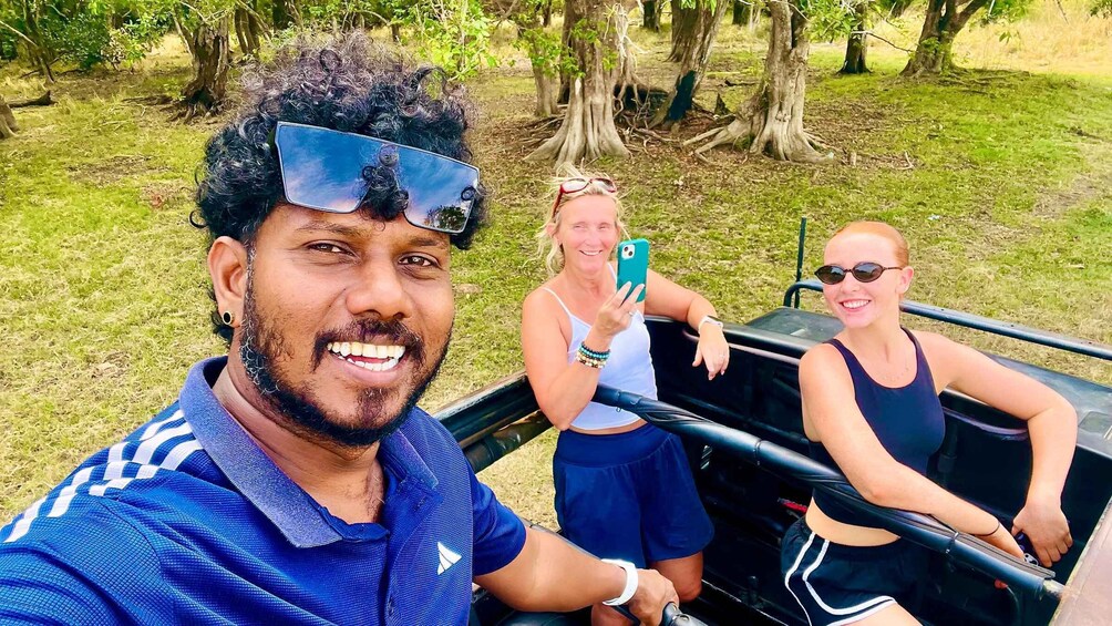 Three people in a vehicle, surrounded by trees and grass. 2