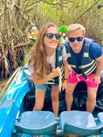 Two people on a boat in a mangrove area. 5