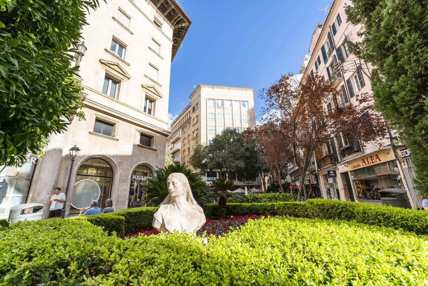 A statue in a garden with buildings in the background. 4