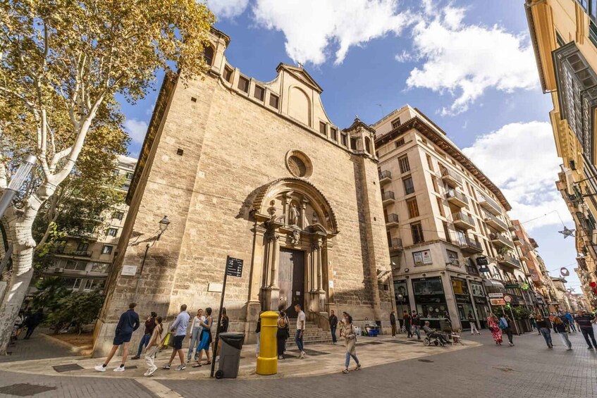 A historic building with a large arched entrance, surrounded by pedestrians and modern buildings. 3