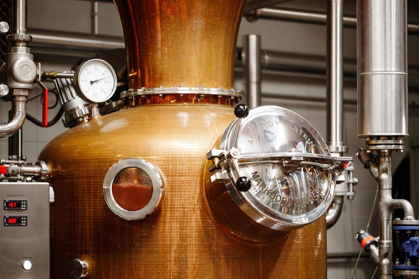 A distillation apparatus with gauges, a control panel, and a copper vessel. 1