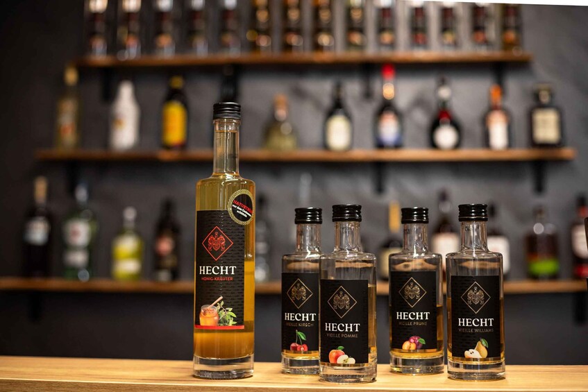 A selection of Hecht brand liqueurs on display with a blurred background of various bottles. 2