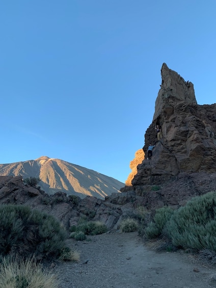 A rocky terrain with a person climbing a large rock formation. 3
