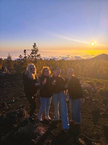 A group of people standing on a rocky terrain with a sunset in the background. 2