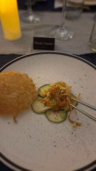 A plate with a fried item, sliced cucumbers, shredded vegetables, and a fork. 3