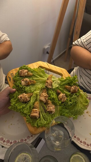A person holding a wooden board with a salad on it. 5