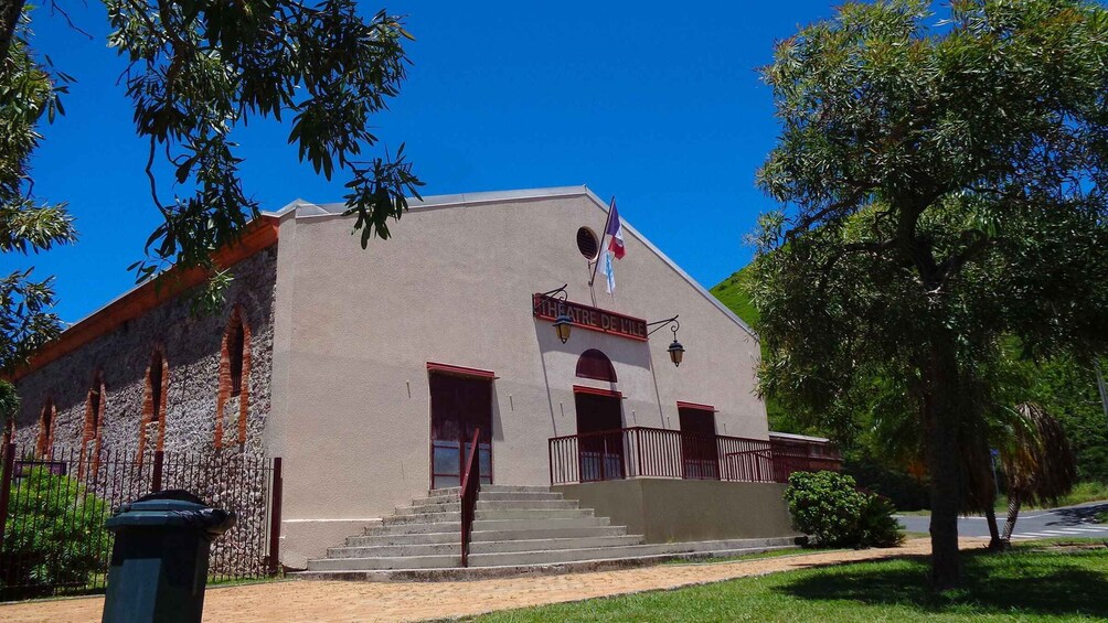 A theater building with a red roof, a flag, and a staircase leading to the entrance. 5