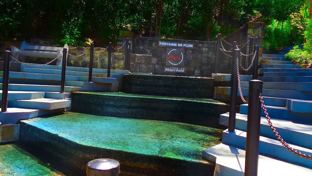 A fountain with steps leading up to it, surrounded by a chain-link fence. 1