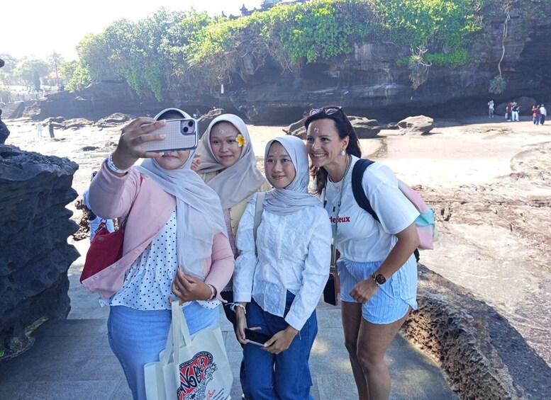 A group of people taking a selfie in a rocky outdoor setting with trees in the background. 2