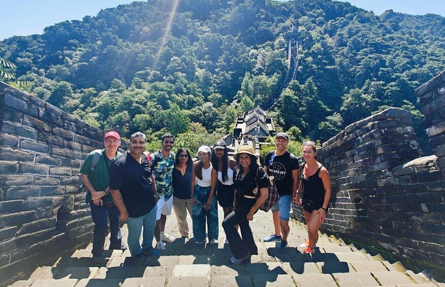 A group of people standing on a stone staircase with a mountainous landscape in the background. 1