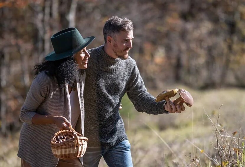 Two people in an outdoor setting, one holding a basket and the other holding a loaf of bread. 2