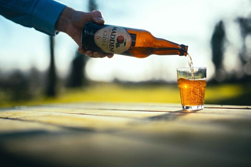 A hand pouring cider from a bottle into a glass. 5