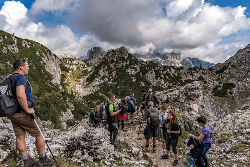 A group of hikers on a rocky mountain trail with a clear sky and distant mountains. 3