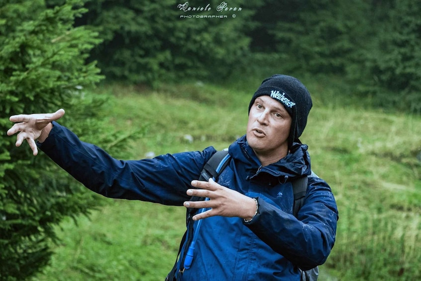 A person in a blue jacket and beanie pointing to the side. 2