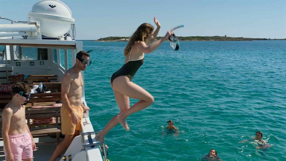 A woman jumping into the water from a boat, people swimming, and a clear blue sea. 2