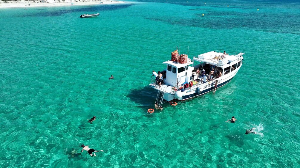 A boat with people swimming and snorkeling in clear turquoise waters. 1