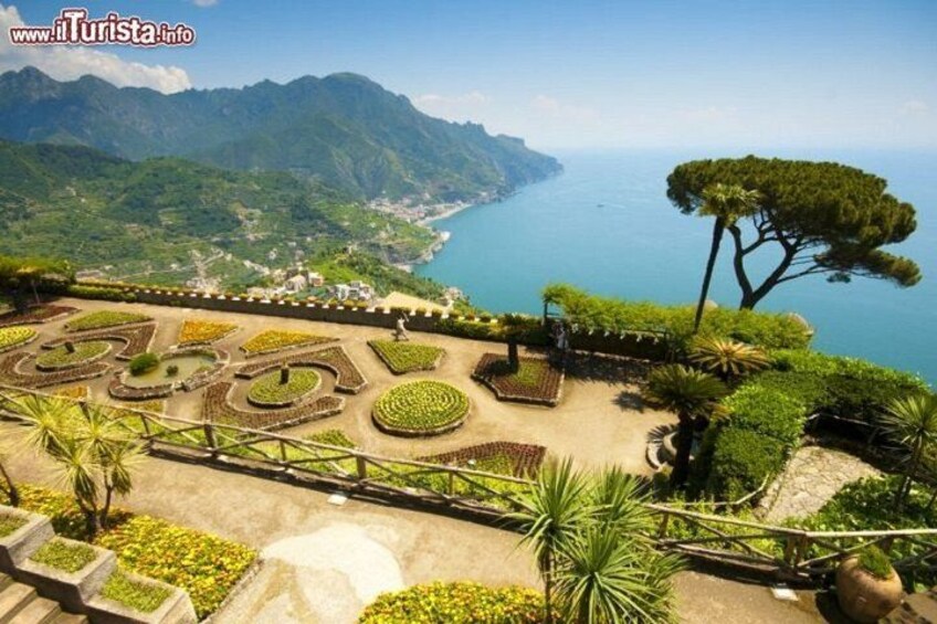 A landscaped garden with geometric patterns, a large tree, and a coastal view. 3