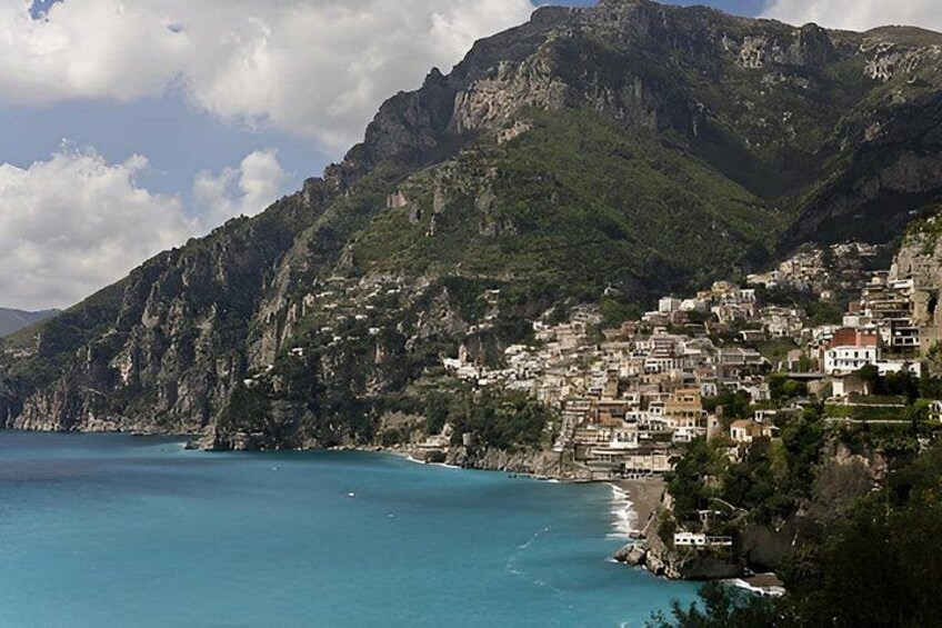 A coastal town nestled against a mountainous backdrop with a clear blue sea. 2