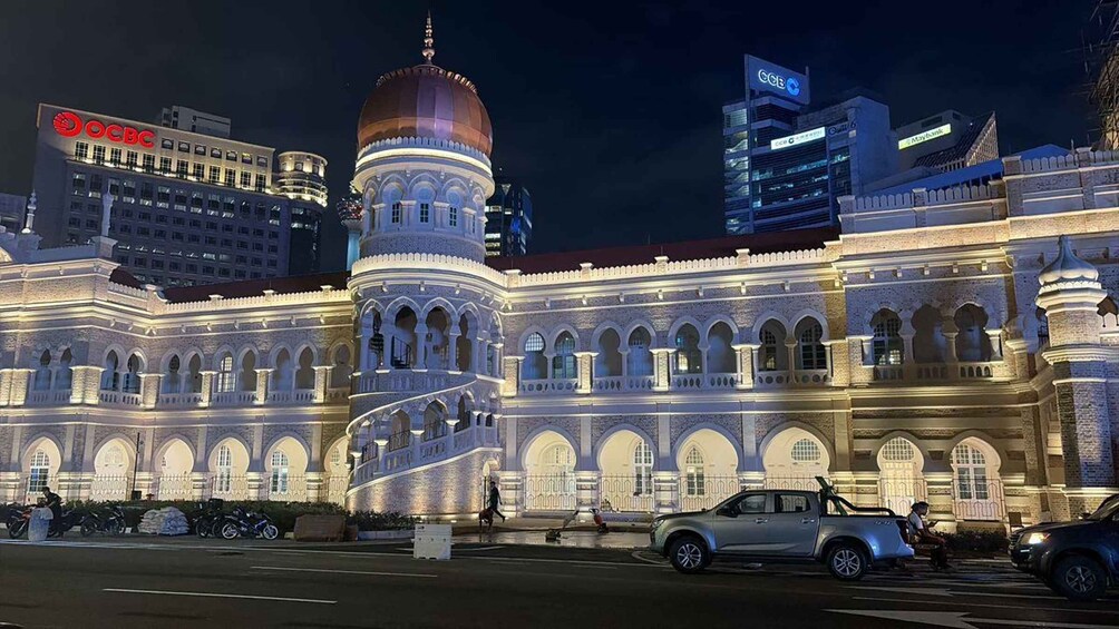 A historic building with a dome and arches, surrounded by modern buildings with illuminated signs. 2