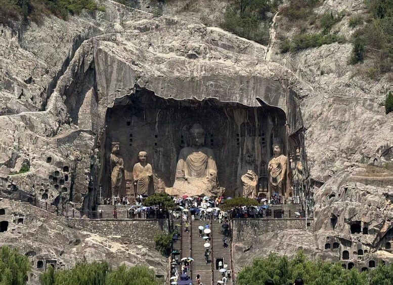 A large rock-cut Buddha statue complex with multiple Buddha figures and a crowd of visitors. 5