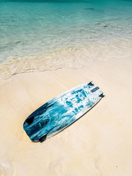 A surfboard on a sandy beach with clear turquoise water. 4