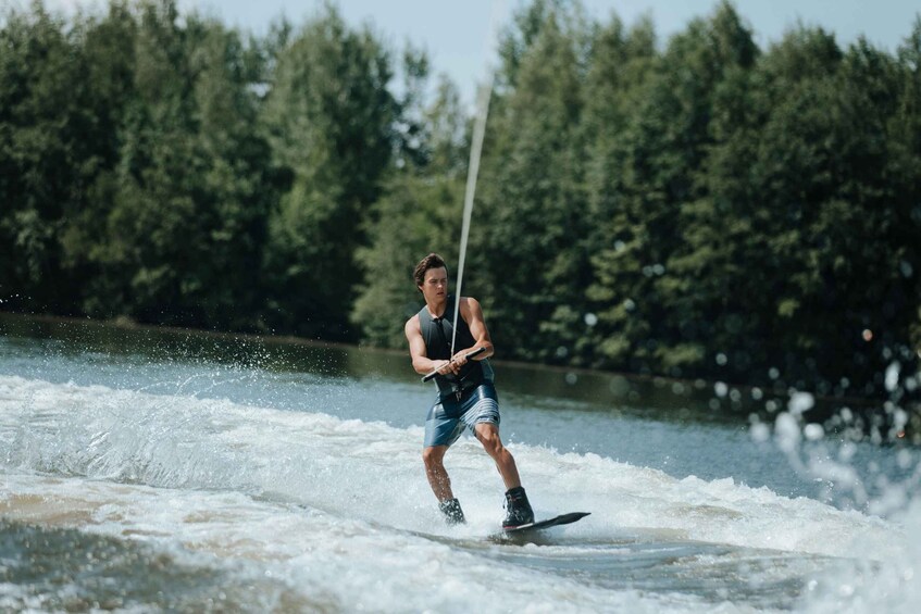 A person wakeboarding on a river with trees in the background. 5