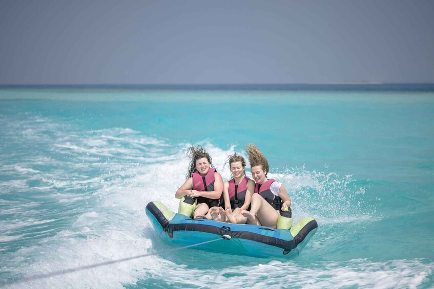Three people on a blue inflatable raft in turquoise water. 1