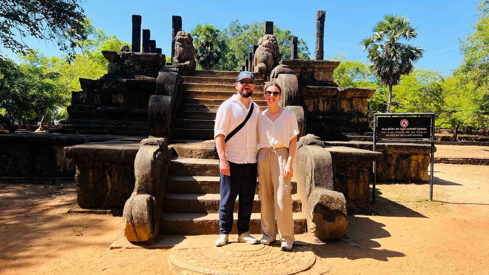 A couple standing in front of ancient stone structures with a warning sign. 5