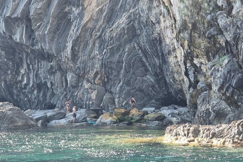 A rocky coastal area with people standing on rocks near the water. 2